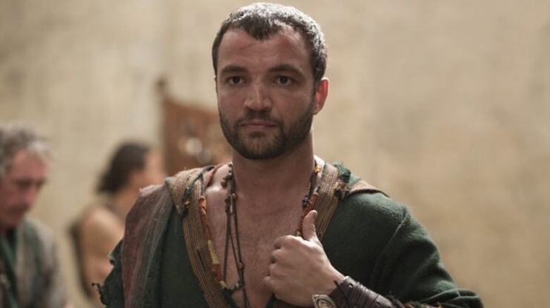 Ashur holds the collar of his tunic on "Spartacus: House of Ashur" (2025)