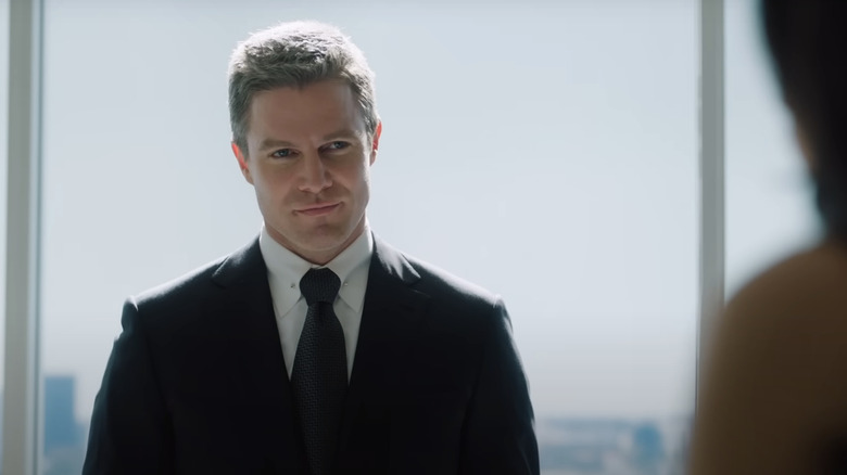 Ted Black smirks in front of a large window in "Suits: LA" (2025)