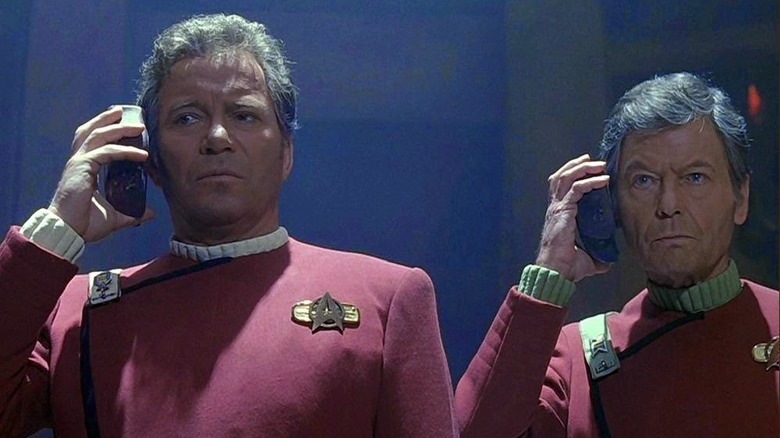 Kirk and McCoy hold translators to their ears Star Trek