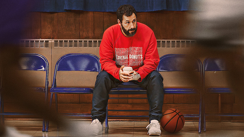 Adam Sandler sits on the bleachers