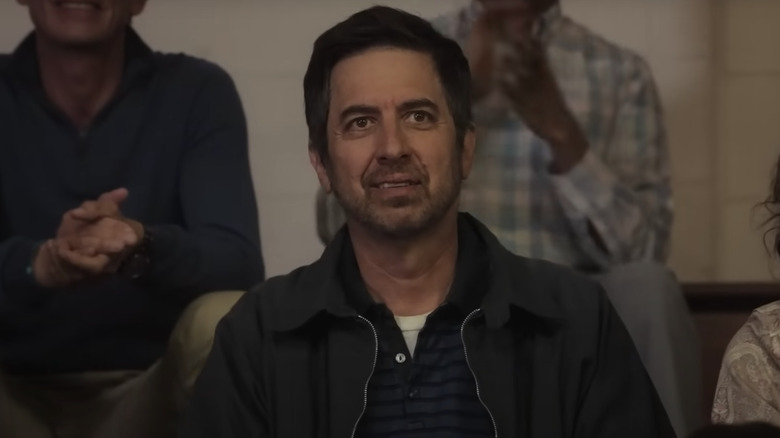 Leo Russo wearing collared shirt and jacket sitting in stands