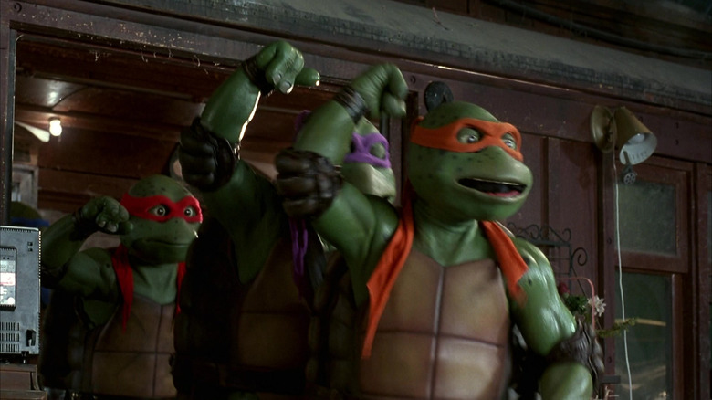 The Tennage Mutant Ninja Turtles with arms raised