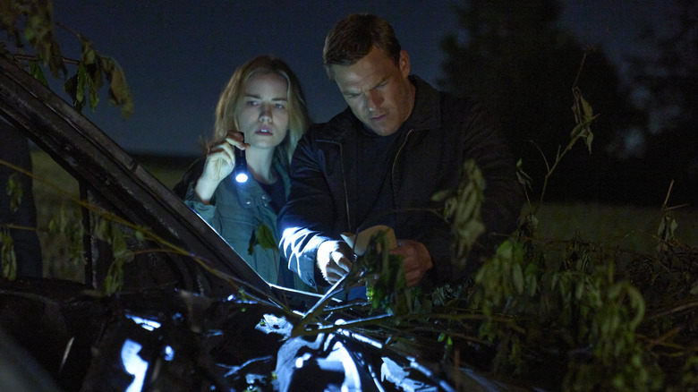 Roscoe and Reacher looking at destroyed car with flashlight