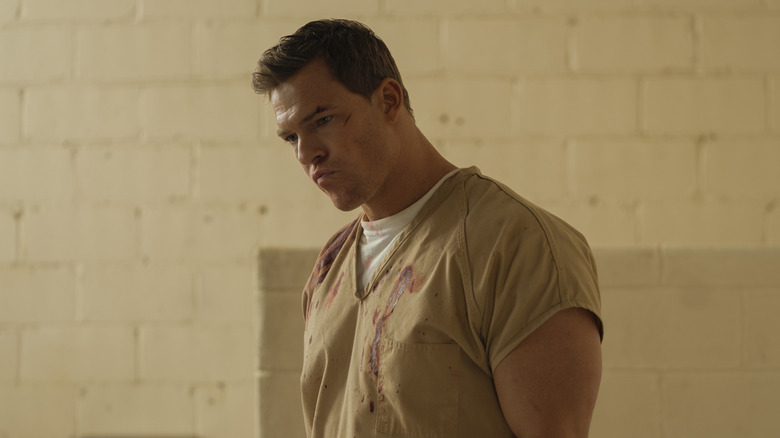 Jack Reacher wearing beige bloodstained prison uniform