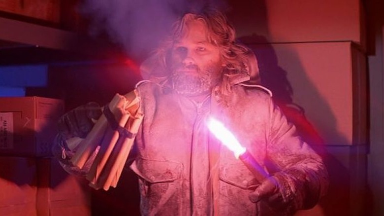 Kurt Russell holding dynamite and a flare in The Thing