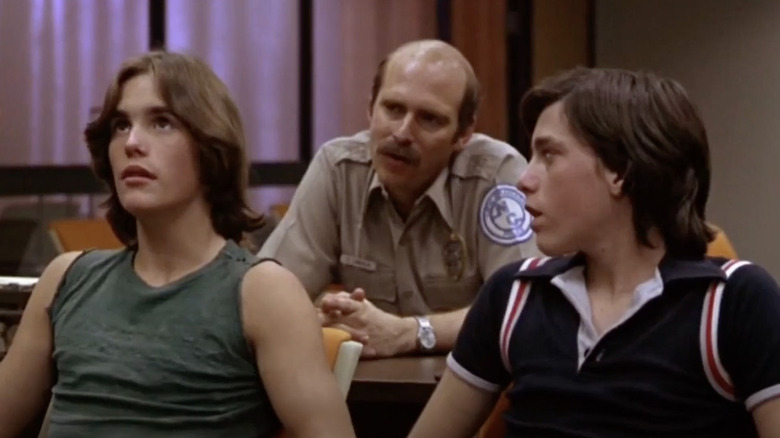 Teens sit in front of cop