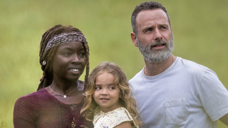 Rick, Michonne and kid smile and look into distance