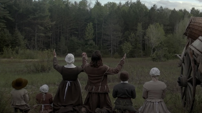 Family kneeling and praying in front of forest The Witch