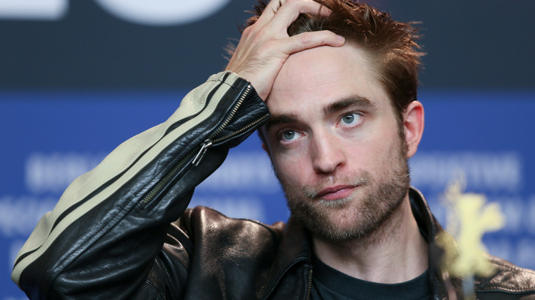 Robert Pattinson holds his head