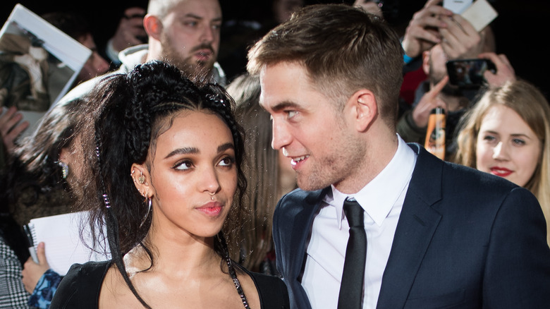 Robert Pattinson standing by FKA Twigs