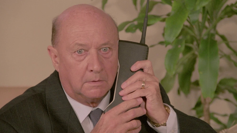 Donald Pleasance holds old cell phone