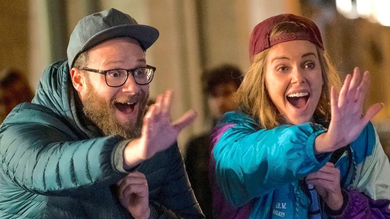 Seth Rogen and Charlize Theron laugh and wave