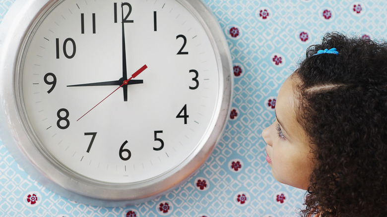 Young girl looking at clock