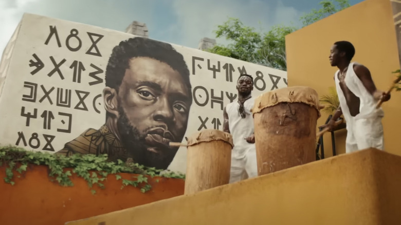 Mural of T'Challa beside two drummers