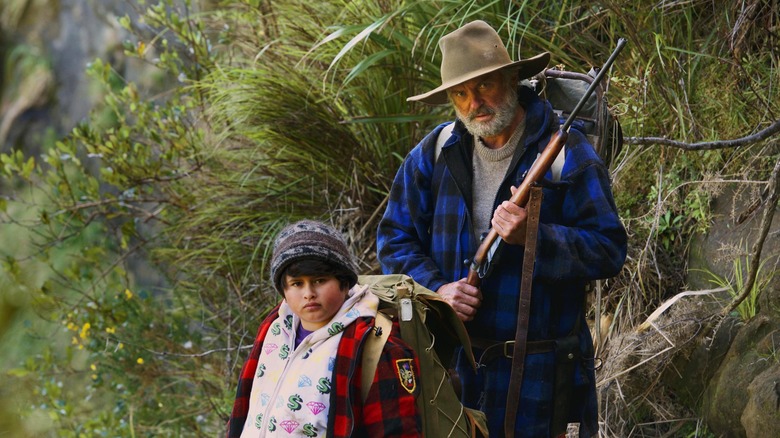 Sam Neill holds a rifle