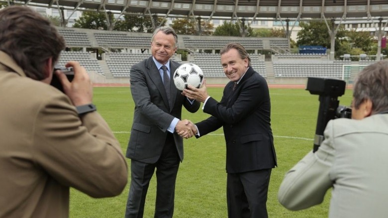 Sam Neill holds a soccer ball