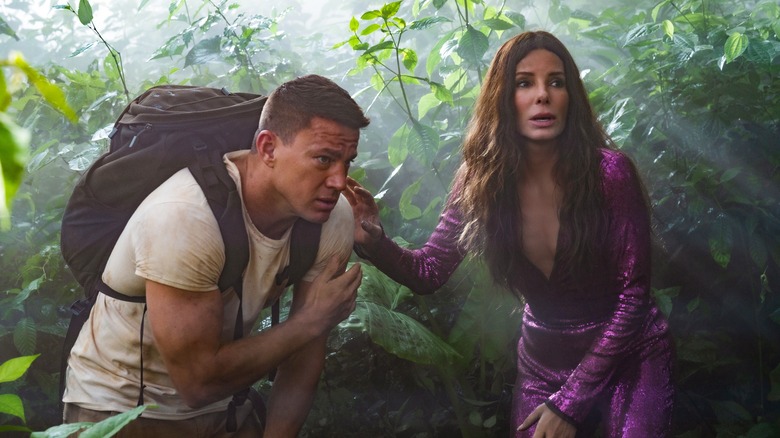 Channing Tatum and Sandra Bullock huddled together in "The Lost City"