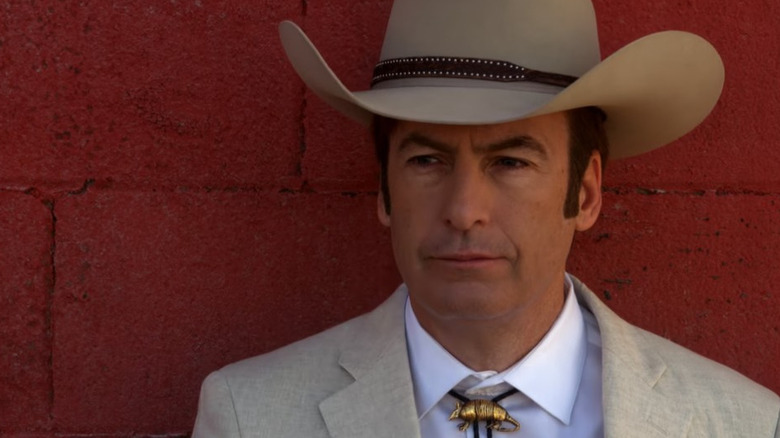 Jimmy McGill wears a cowboy hat in front of a brick wall