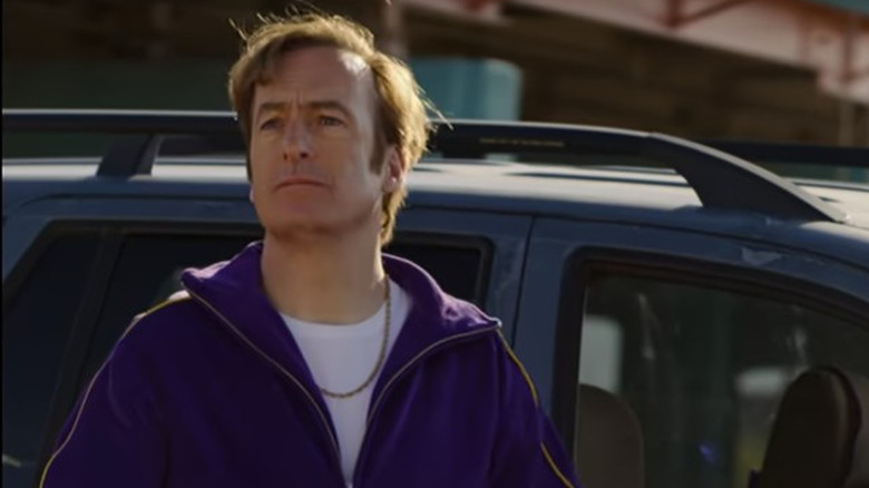 Jimmy McGill stands in front of a car 