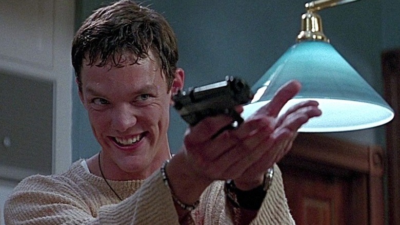 Stu Macher holding a gun and grinning