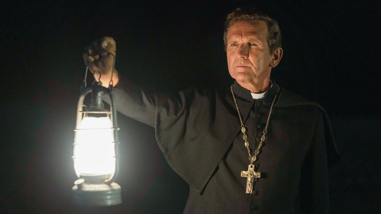 Father Renaud holding a lantern