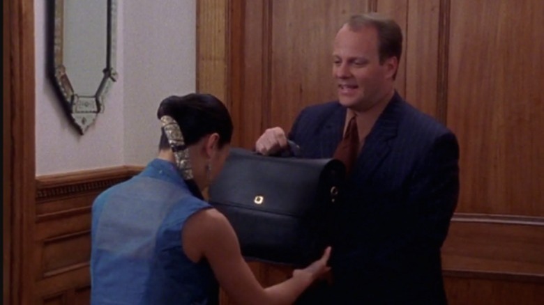 A female servant bowing and grabbing a man's briefcase