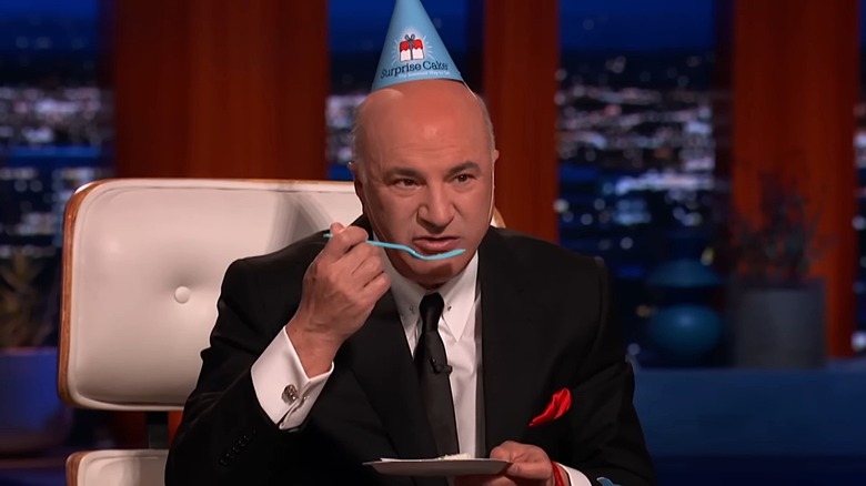 Mr. Wonderful eating a slice of cake while wearing a party hat