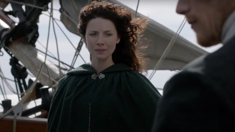 A woman stands on the deck of a sailing ship