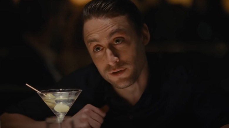 Roman Roy smirking over martini