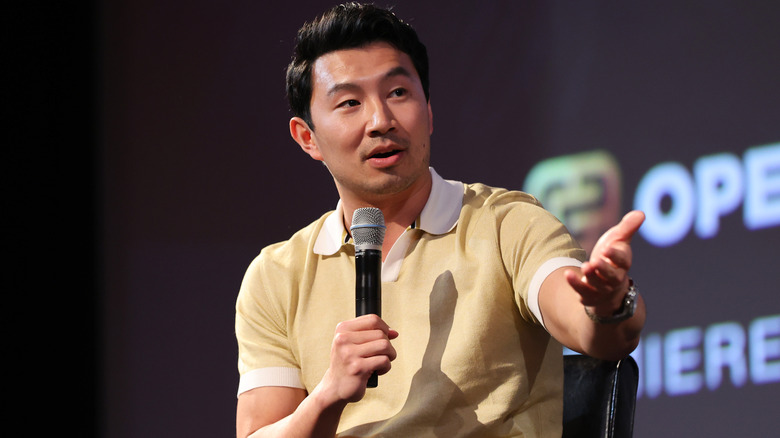 Simu Liu speaking onstage at a Los Angeles Q&A for "Shang-Chi and The Legend of the Ten Rings"