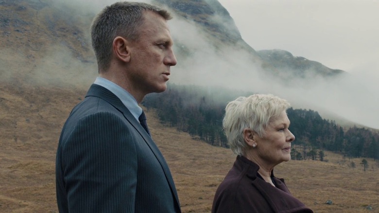 Bond and M stand in front of a fog-covered mountain