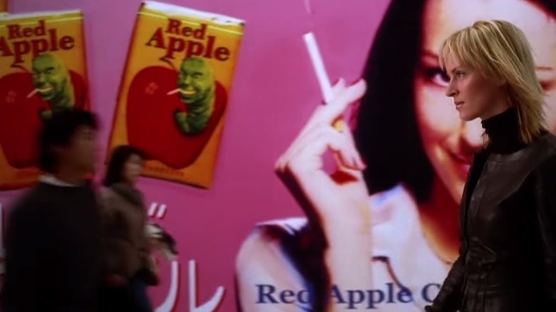 The Bride walks past a Red Apple Cigarettes billboard