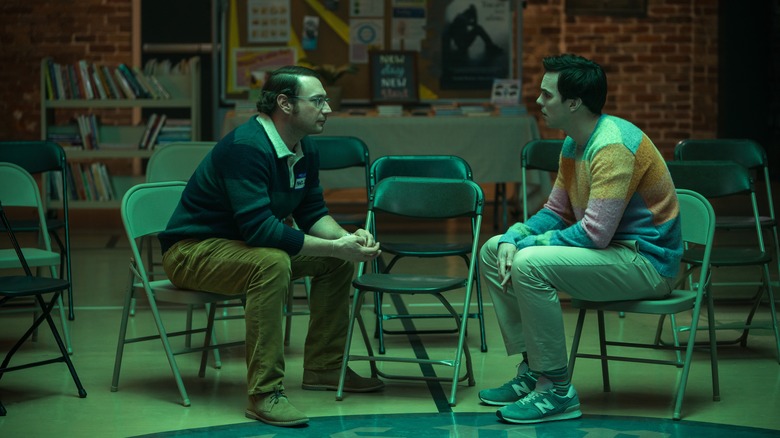 Brandon Scott Jones and Nicholas Hoult sitting on fold out chairs in a gym