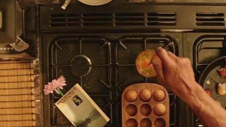 Hobbs makes breakfast with book next to eggs