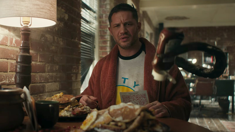 Eddie Brock looking at Venom tentacle holding ketchup bottle