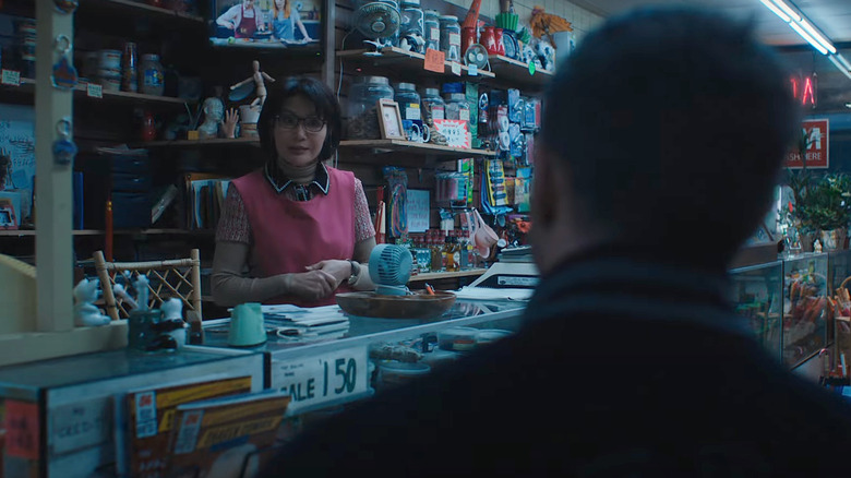 Mrs. Chen holding her hands at the counter Venom 2