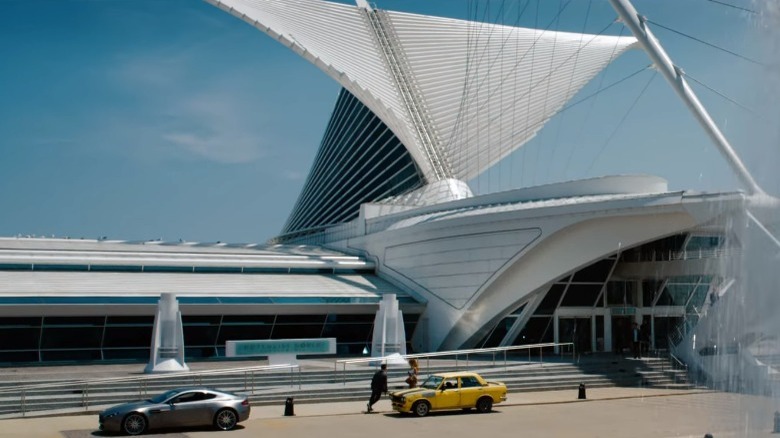 Sam and Carly get in car in front of a modernist white building