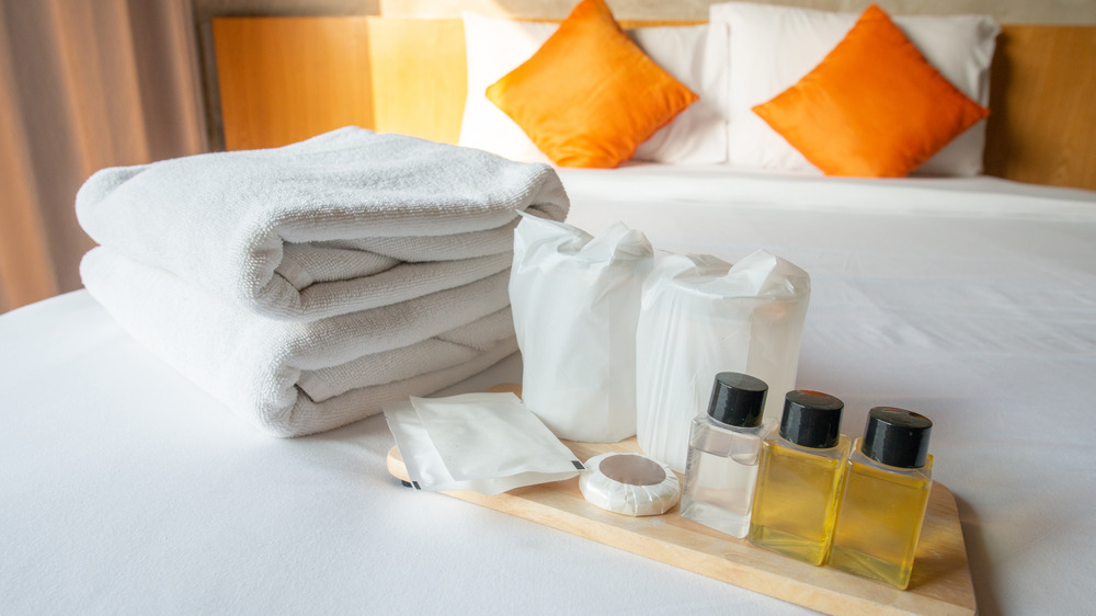 hotel bed with towels, soaps, shampoo