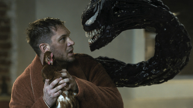 Eddie Brock holding a chicken next to Venom