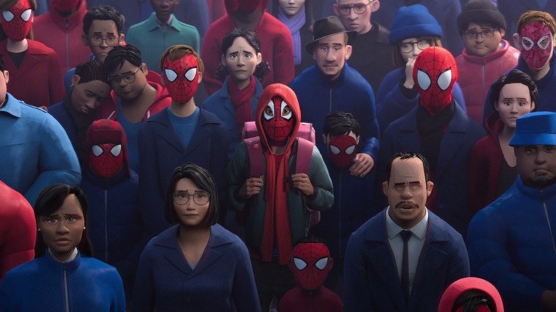 Miles wearing a Spider-Man mask and standing in a crowd of Spider-Man fans 