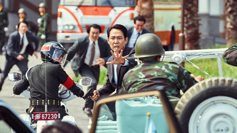 Lee Jung-jae outstretching a hand to motorcyclists in Hunt