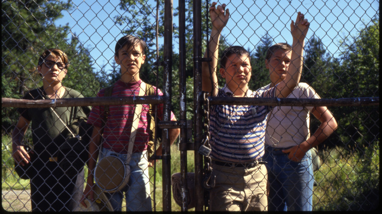 The Stand By Me kids behind a chain link fence