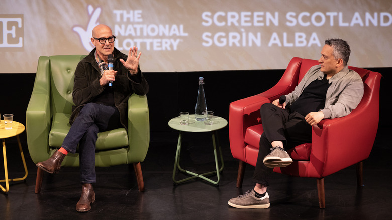 Stanley Tucci and Joe Russo sitting in chairs on stage