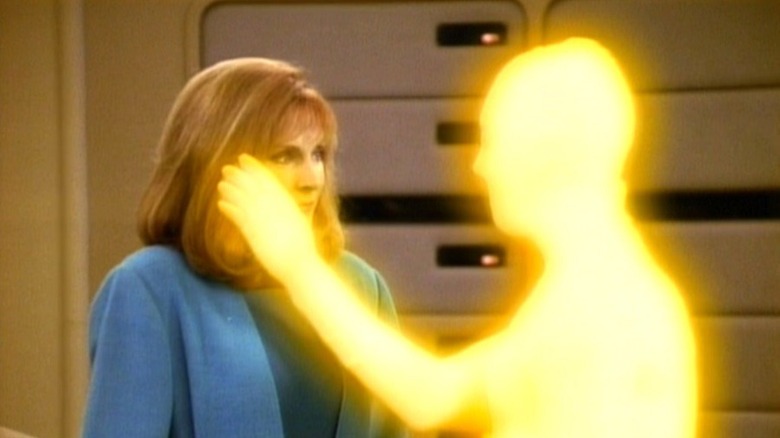 A glowing being touches Dr. Crusher's face