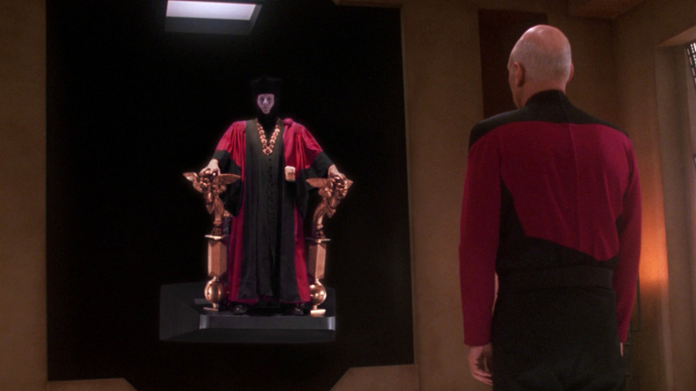 Q in judge uniform, backing away from Picard