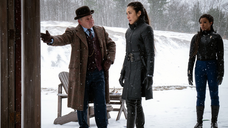 Carl leads Philippa toward a door in a snowy field as Michael watches