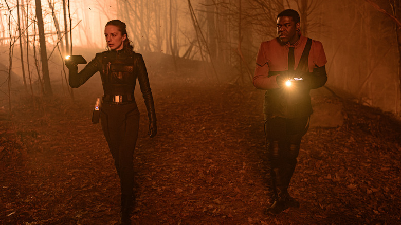 Rachel and Quasi walk together in the woods with flashlights