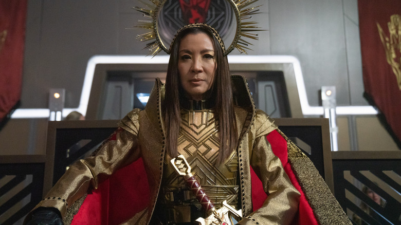 Philippa Georgiou wears a gold outfit while sitting on a throne