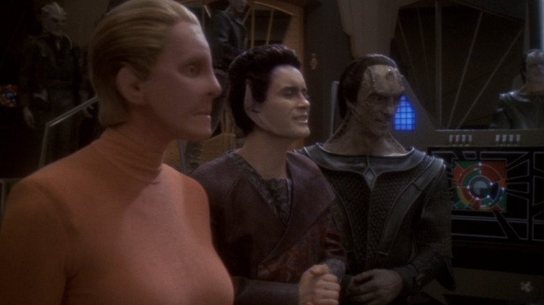 The female Changeling, Weyoun, and Dukat watch a moniter