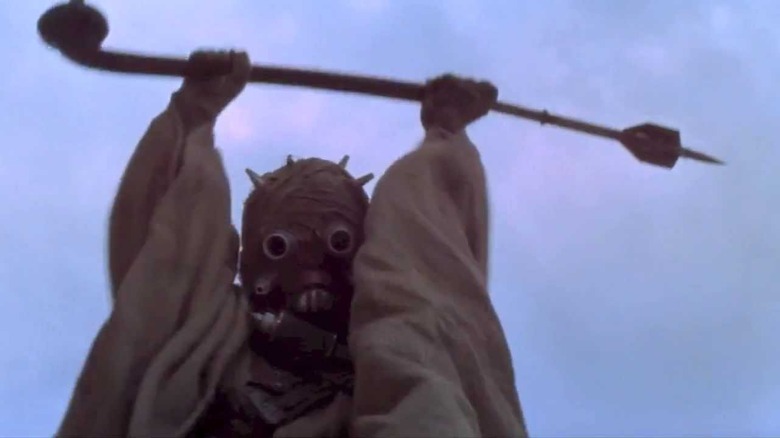 A Tusken Raider cheers and holds up his weapon in "Star Wars" (1977)